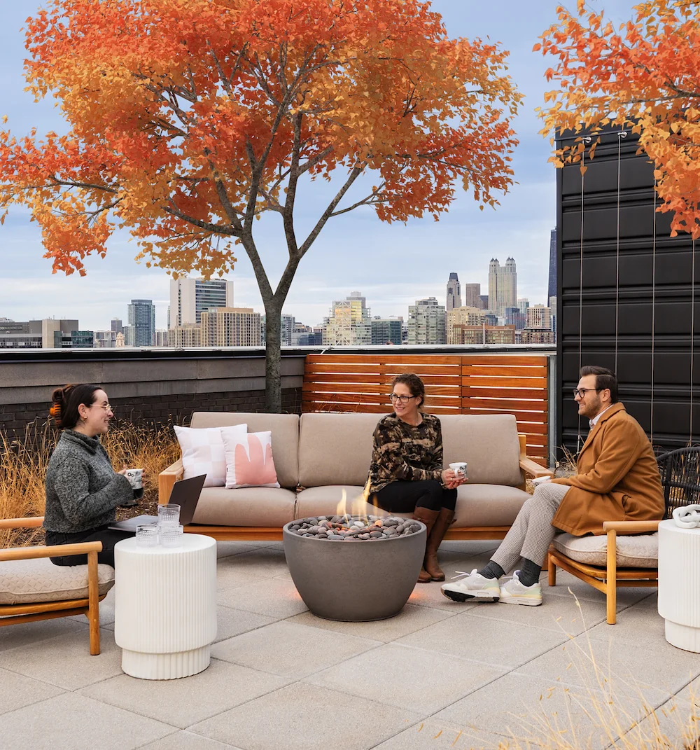 Business people sitting on couches around a fire on an office roof garden
